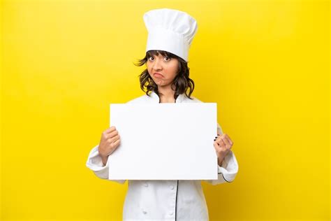 Joven chef mujer latina aislada de fondo amarillo sosteniendo un cartel vacío Foto Premium