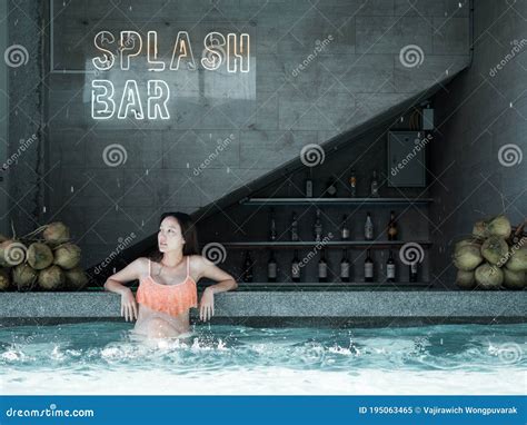 Asian Woman In Bikini Sitting In Front Of Swimming Pool Bar Stock