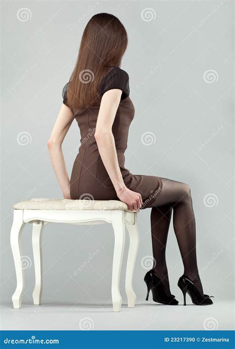 Ragazza Elegante Del Brunette Che Si Siede Su Una Presidenza Fotografia