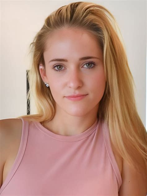 A Woman With Long Blonde Hair Wearing A Pink Top And Looking At The Camera While Standing In