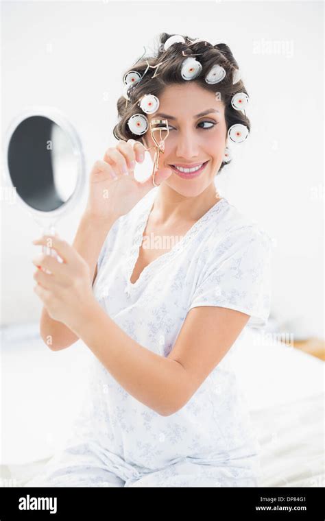 Pretty Brunette In Hair Rollers Looking In Hand Mirror And Using
