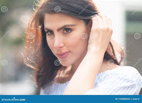 Shy But Flirty Brunette Tucking Her Hair Behind Her Ear Closeup Sunny Warm Day Stock Photo