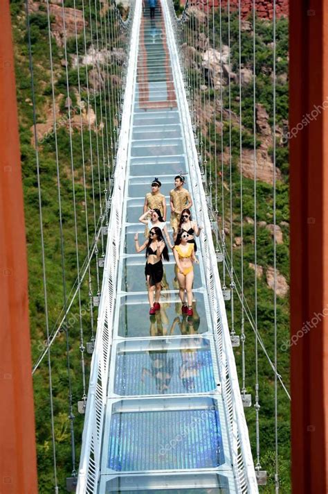 Bellezas chinas en bikini posan en el puente de vidrio D en el Gran Cañón Wan An Shan en la