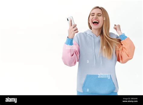 Portrait d une fille blonde enthousiaste et gaie gagnant en ligne de compétition levant les