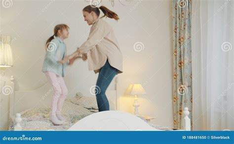 Mother And Daughter Jumping In Bed Having Fun Holding Hands Enjoying