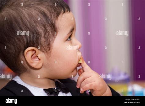 Adorable Happy Baby Eating Chocolate Wearing Suit And Bow Tie Stock