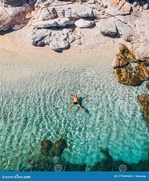 Aerial Photo of Man Lying on the Water in STAR Pose on Rocky Pebbly