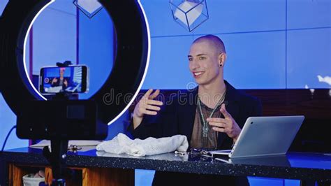 Medium Shot Of A Gay Influencer Man Streaming A Live Video With His Phone At Home Stock Photo