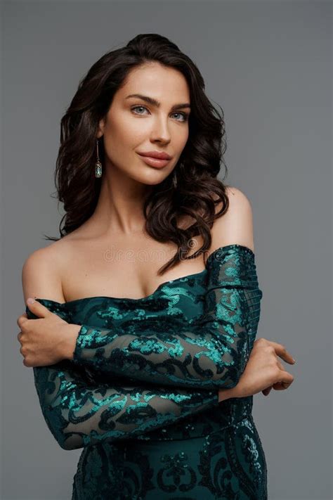 Brunette Impresionante En Un Elegante Vestido Verde De Noche Con Un Fondo Gris Imagen De Archivo