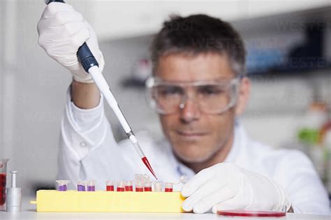 Germany Bavaria Munich Scientist Pouring Red Liquid With Pipette In