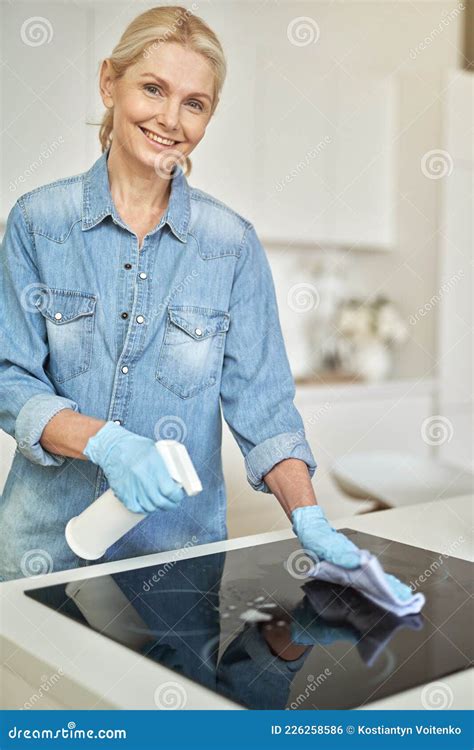 Tidy Mature Blonde Woman In Rubber Gloves Smiling At Camera Cleaning