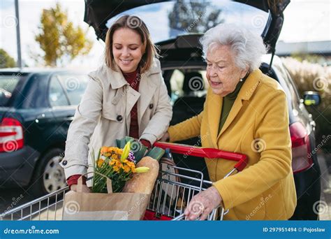 Mature Granddaughter Helping Grandmother Load Groceries In To The Car Senior Woman Shopping At