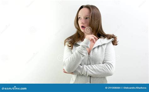 A Young Woman Standing In Front Of A White Wall And Making A Surprise