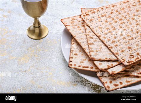 Plate With Jewish Flatbread Matza For Passover And Cup Of Wine On Light