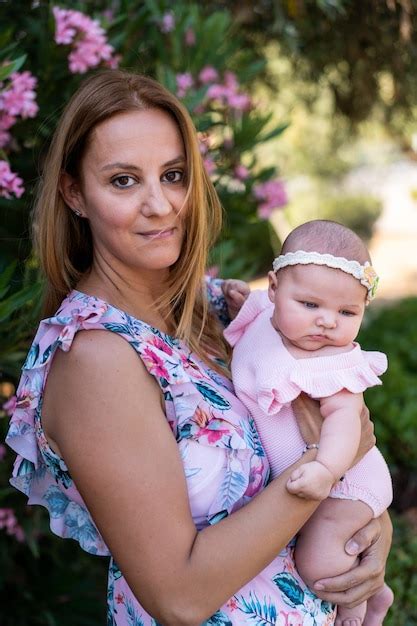 Jeune Mère Avec Une Robe à Fleurs Tenant Sa Petite Fille Photo Gratuite