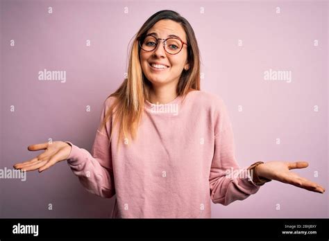 Belle Femme Blonde Avec Les Yeux Bleus Portant Un Chandail Et Des Lunettes Sur Fond Rose