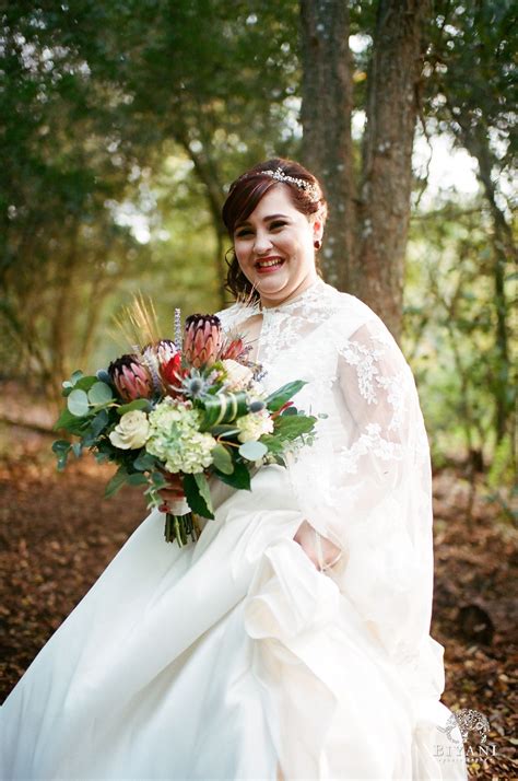 Sweetest bride smiling holding her bouquet wearing a caped wedding gown