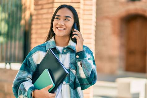 Joven Estudiante Latina Sonriendo Feliz Usando Un Smartphone En La Ciudad Imagen De Archivo