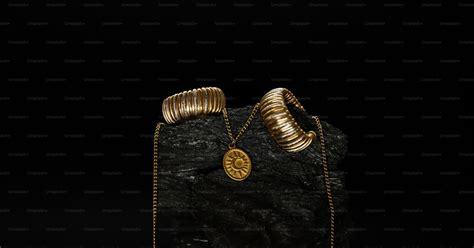gold jewelry displayed   dark textured surface photo minimalist