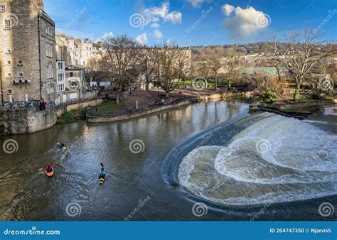 Three Canoists On The River Avon Alongside The Raging Water Of Pulteney