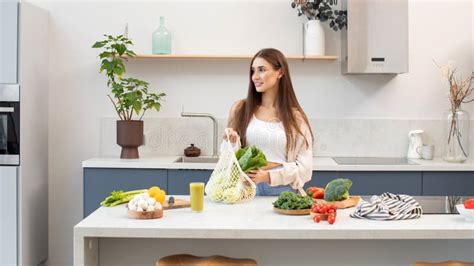 An Attractive Brunette Pulls Fresh Vegetables Out Of A Reusable Bag Vegetarianism Stock Image