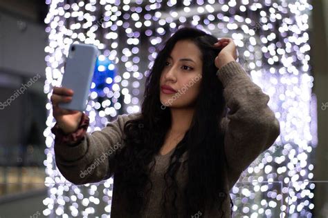 Chica latina está de compras en un centro comercial se toma una selfie en su teléfono celular