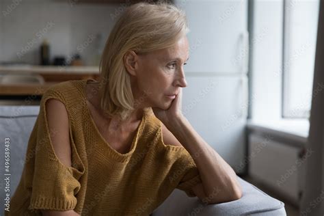 Depressed Mature Blonde Lady Looking At Window Away With Unhappy Frustrated Disappointed Stare
