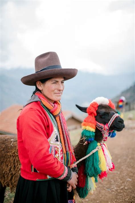 Quechua woman in traditional outfit standing on rural road with cute ...