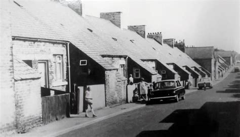 An Old Black And White Photo Of People Standing In Front Of Some Brick