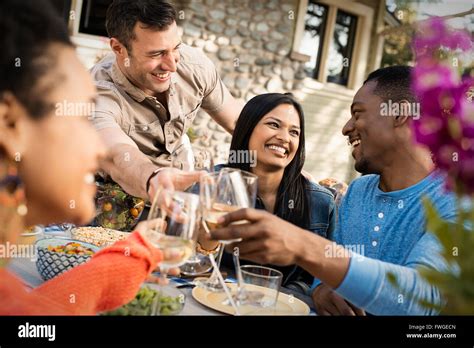 Friends Around A Table Men And Women Laughing And Clinking Wine