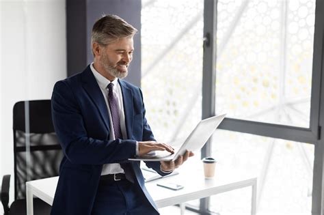 Premium Photo Portrait Of Smiling Mature Businessman In Suit Using Laptop In Office