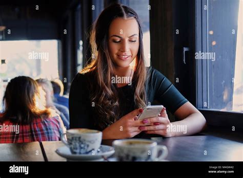 Attractive Brunette Woman Texting An SMS In A Cafe Stock Photo Alamy