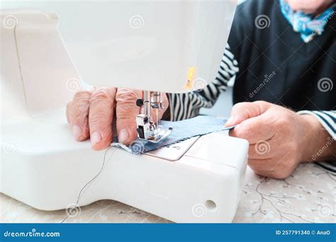 An Old Male Tailor Sews On An Electric Sewing Machine Close Up On