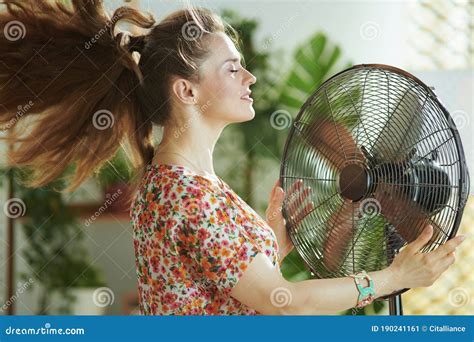 Woman In Modern House In Sunny Hot Summer Day Fanning Herself Stock