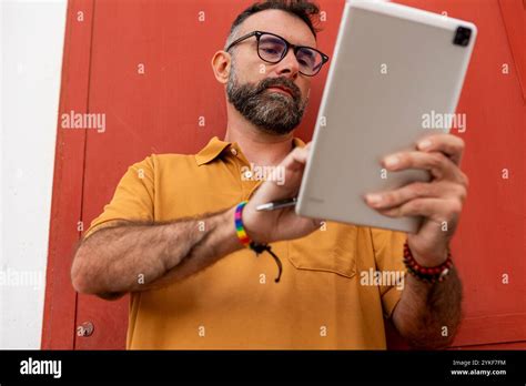 A Middle Aged Gay Man With A Beard Wearing Glasses And A Rainbow Wristband Focused On Using A