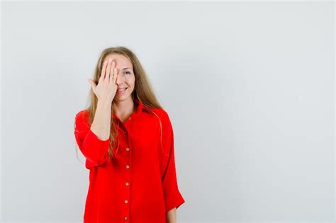 Dame blonde couvrant un œil avec la main en chemise rouge et à l excitation Photo Gratuite