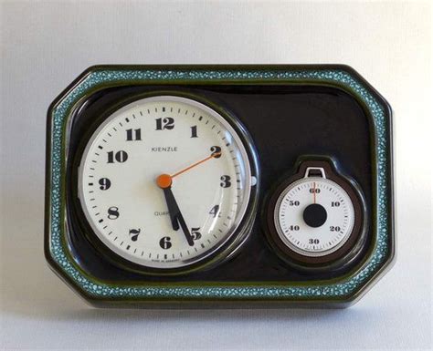 Two Clocks Sitting Side By Side On A White Surface With Blue And Green