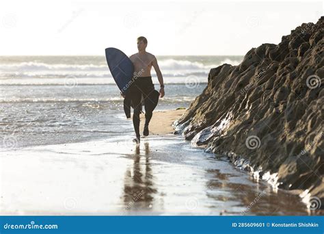 A Man With A Naked Torso Walking On The Beach Holding A Surfboard Stock Image Image Of