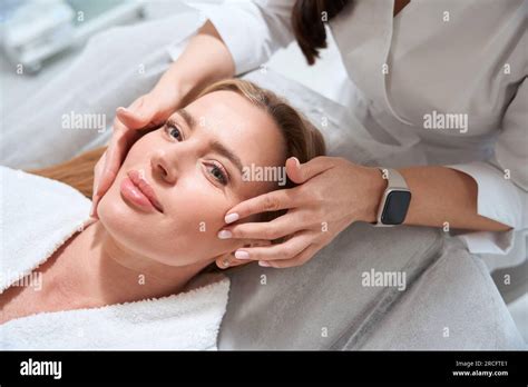 Female Masseuse Makes A Professional Facial Massage To A Patient Stock