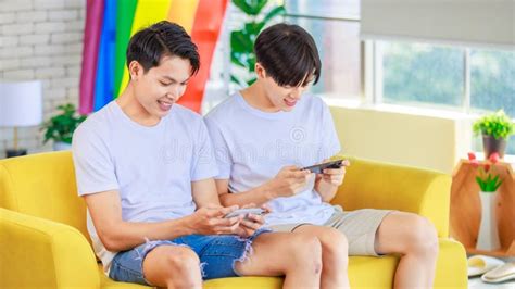 Two Asian Cheerful Teenager Male Gay Men Lover Couple Partner Sitting Smiling On Sofa Holding