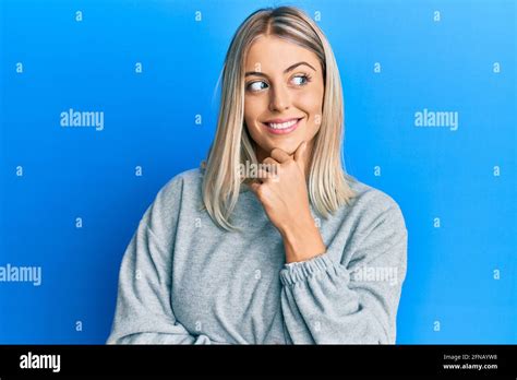 Belle femme blonde portant des vêtements décontractés avec la main sur le menton pensant à la