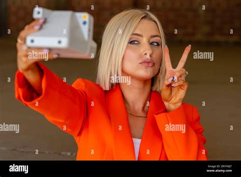 A Lovely Blonde Model Poses Outdoors Using Her Camera While Enjoying