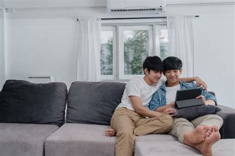 Jeune couple gay avec tablette à la maison Les hommes LGBTQ asiatiques heureux se détendent