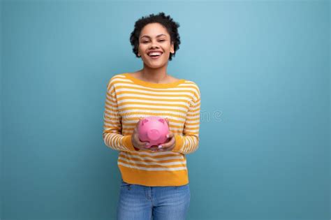 Feliz Afro Brunette S Jovem Latina Segurando Um Porquinho De Dinheiro Foto De Stock Imagem