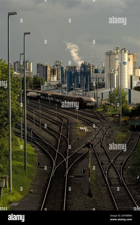 A Sprawling Industrial Landscape In The Background With Railroad Tracks