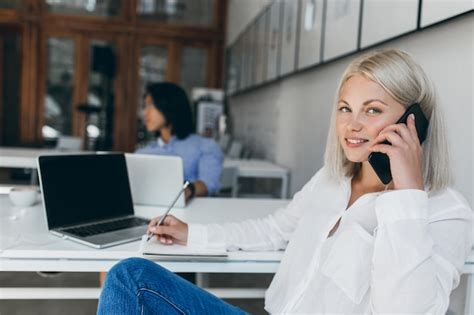 Free Photo Cute Blonde Secretary In White Blouse Talking On Phone And Writing Data In Notebook