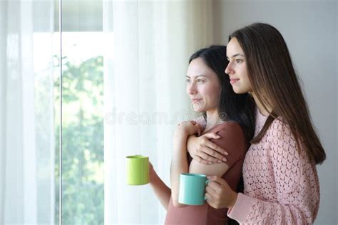 Happy Interracial Lesbian Couple Drinking Looking Through A Window Stock Photo Image Of House