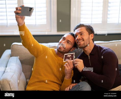 Pride Gay Couple Taking Selfie With Ultrasound Scan At Home Stock Photo