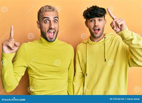Homosexual Gay Pareja De Pie Juntos Usando Ropa Amarilla Señalando Dedo Hacia Arriba Con Idea