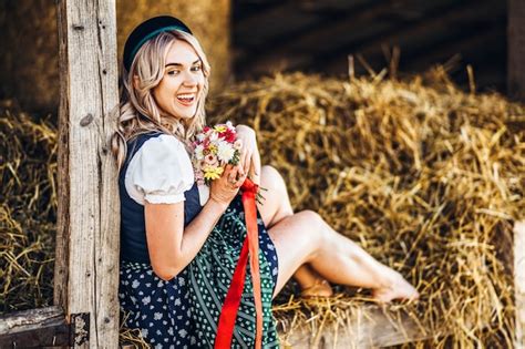 Jolie Blonde En Dirndl Robe De Fête Traditionnelle Avec Bouquet De Fleurs Des Champs Assis Sur